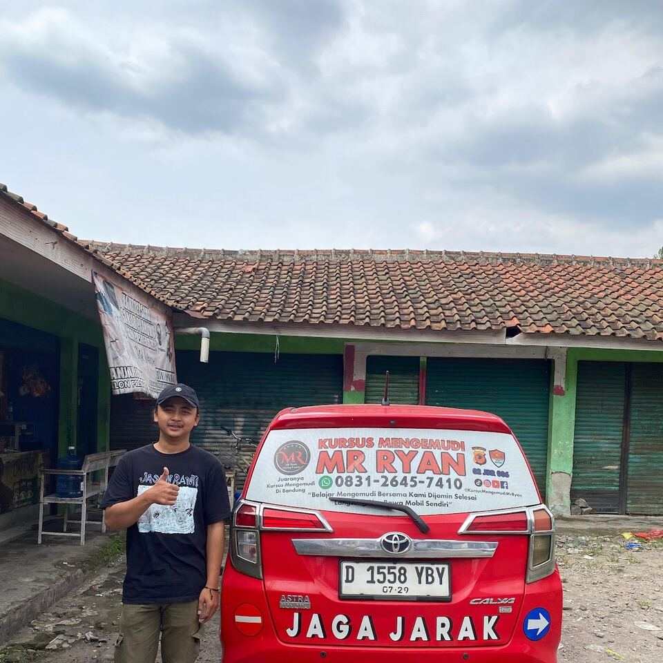 Seorang siswa mengacungkan jempol di depan mobil MR RYAN.